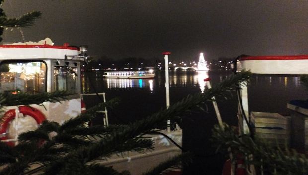 Hamburg - Binnenalster - Vorne die vertäuten Alsterboote, die jetzt Märchenschiffe sind - auf der Alster die Weihnachtstanne und ein Ausflugsboot, das in der Dunkelheit unterwegs ist